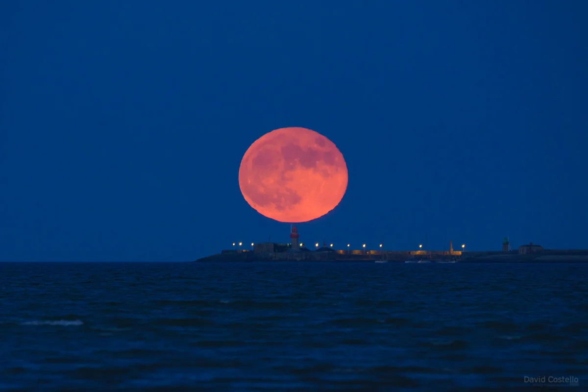 The full moon sits above Dun Laoghaire lighthouse.