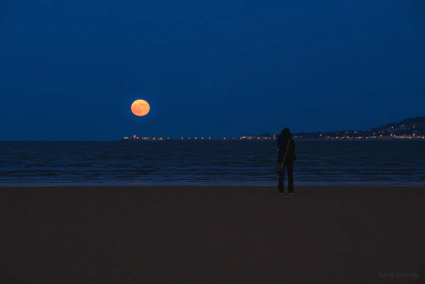 A girl watching the Full Moon rising above Dublin Bay.