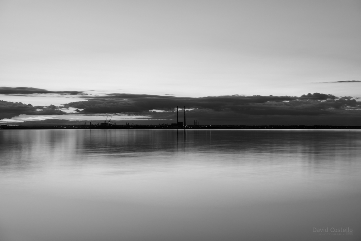 From Dun Laoghaire west pier across Dublin bay in a black and white print.