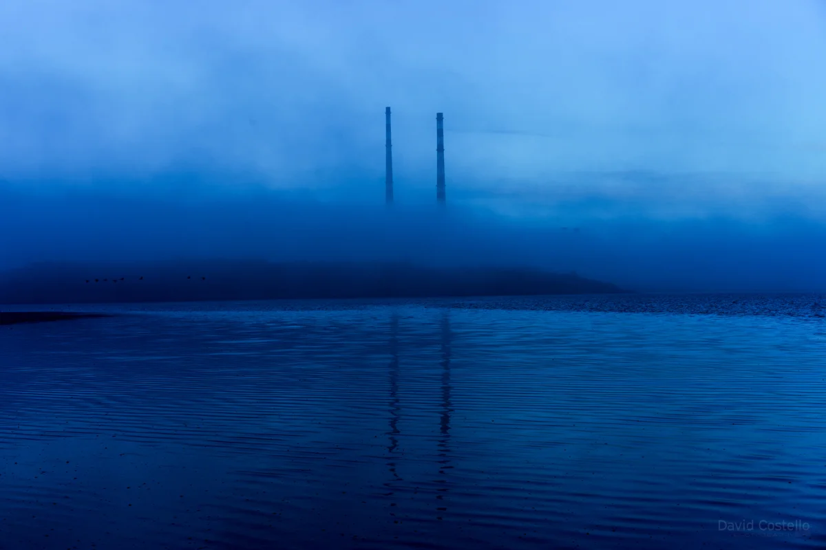 The fog flooding into Dublin Bay and engulfs the Poolbeg Towers at dusk on a cold January day.