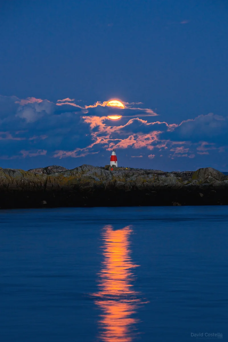 The full moon rising between the Poolbeg Chimneys in Dublin after breaking through the cloud.