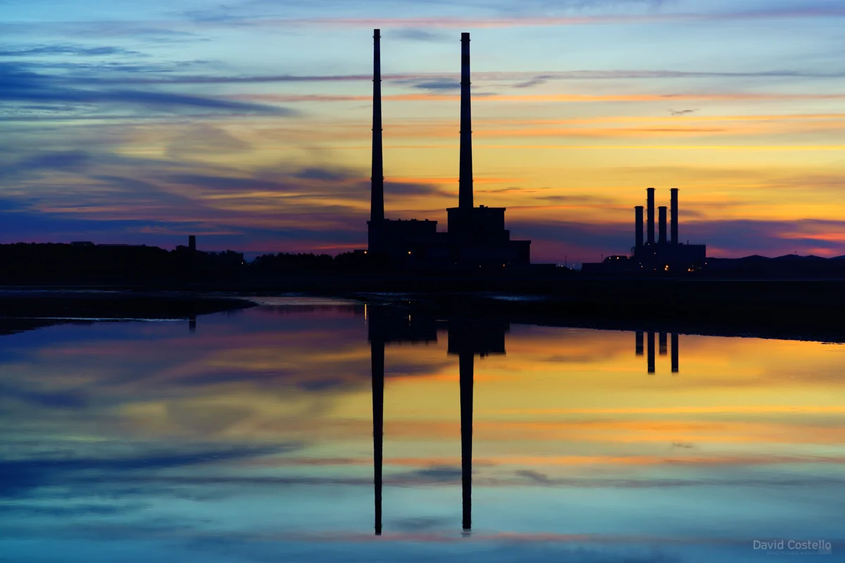 The Poolbeg Towers reflecting in the bay as morning arrives, the summer sky lights up in a beautiful rainbow of colour.