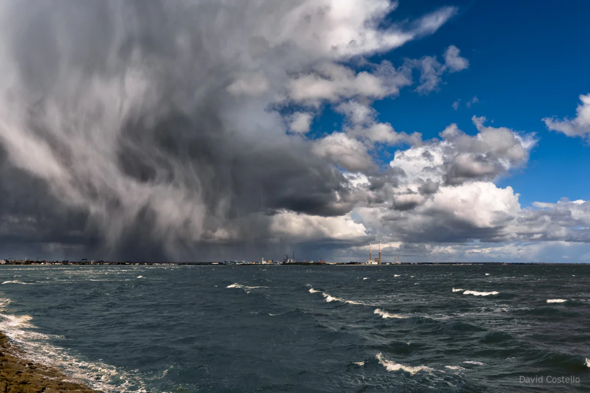 Poolbeg Peninsula from Blackrock as a Spring afternoon is broken in half between the sunny skies and wintry hail in Dublin.