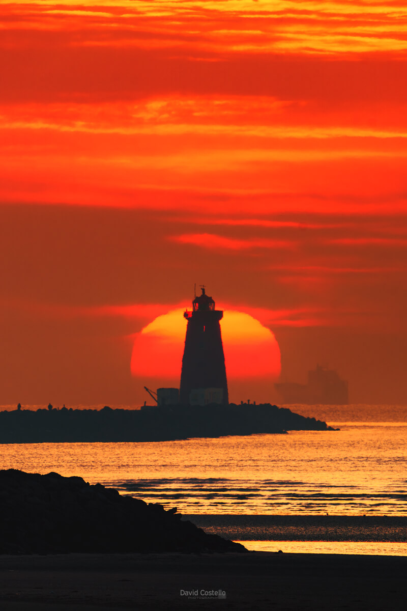 Poolbeg Lighthouse print at sunrise, misty morning over Dublin bay with fiery golden sky.