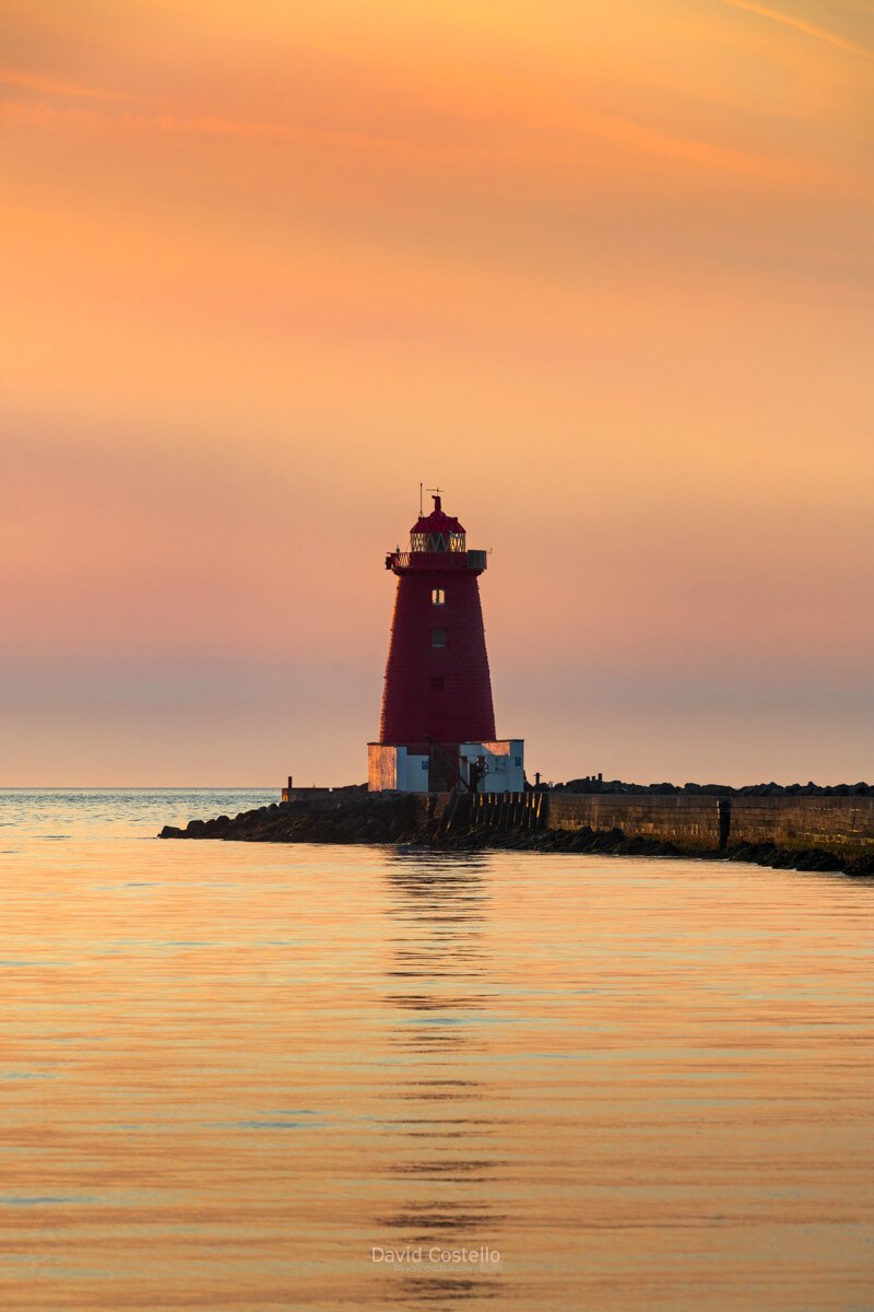 Early morning light falls across Dublin Bay, bringing warm, colourful tones to the sky above Poolbeg Lighthouse.
