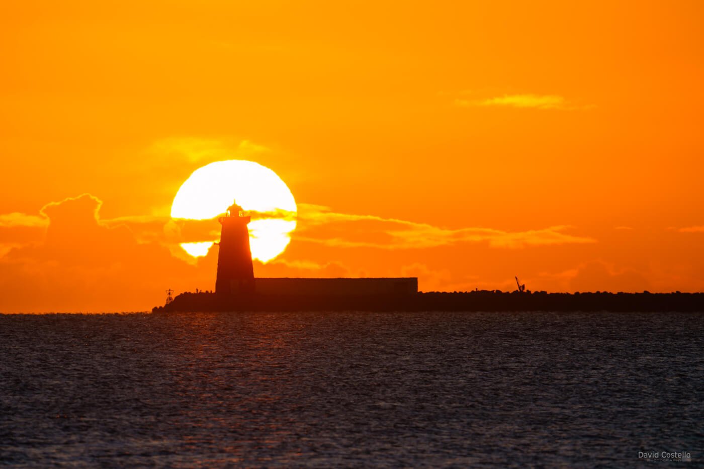 The rising winter sun aligned behind Poolbeg Lighthouse from Clontarf Promenade on a freezing January morning.