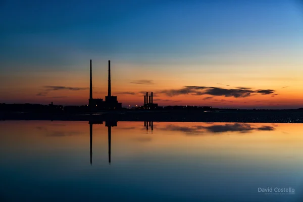 A silhouette at dawn on Sandymount Strand looking towards the Chimneys.
