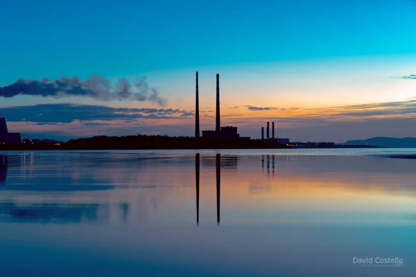 Dublin Towers silhouette at dawn with a colourful sky and reflecting in the sea at Sandymount Strand.