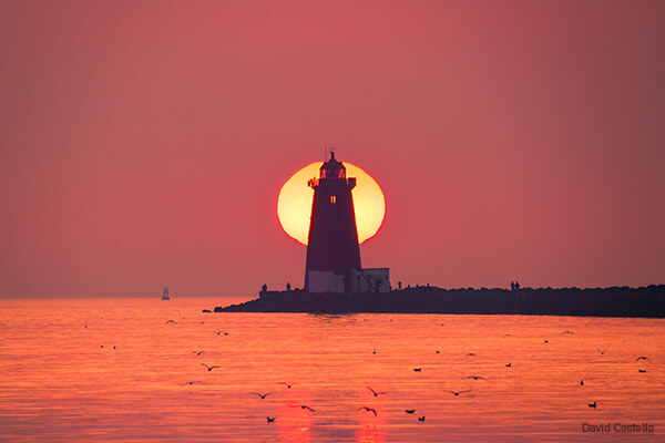 The sun rises behind the Poolbeg Lighthouse early on a spring morning in this print from the Great South Wall in Dublin Bay.