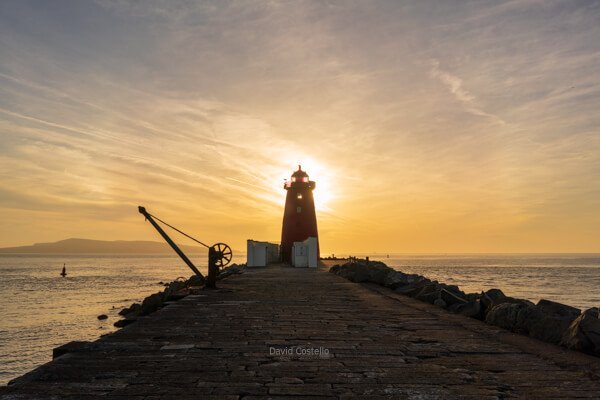 Along The Great South Wall towards the Poolbeg Lighthouse which is reflecting in the water on a calm evening in Dublin.