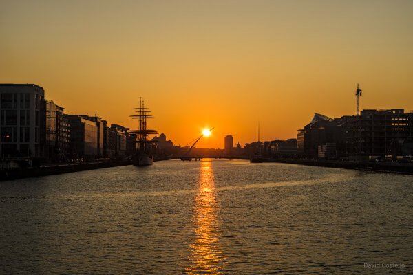 The Sunset touching Beckett Bridge and reflecting along the river Liffey as the city buildings begin to silhouette.