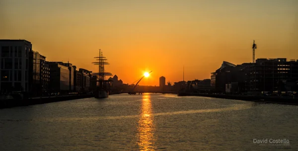 The Sunset touching Beckett Bridge and reflecting along the river Liffey as the city buildings begin to silhouette.