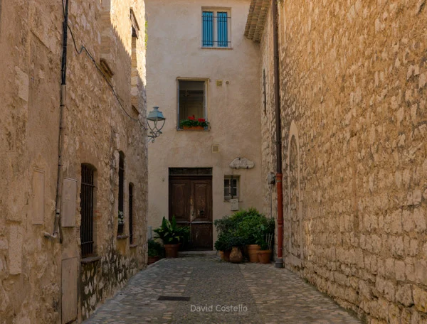 A lantern, old door and plants along a cobblestone passageway in Saint-Paul-de-Vence.